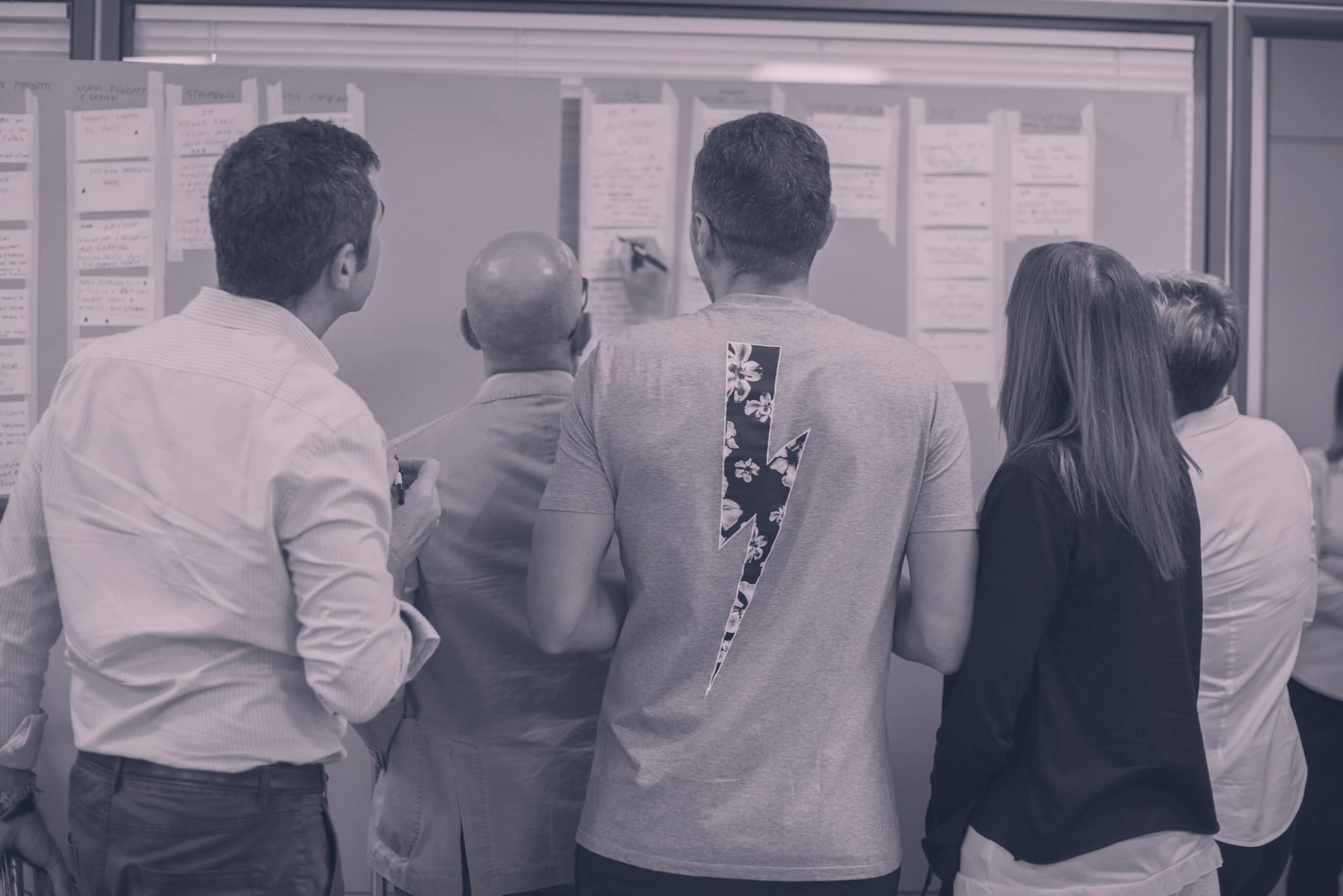Workshop-Gruppe von hinten vor einer Pinnwand mit Notizkarten